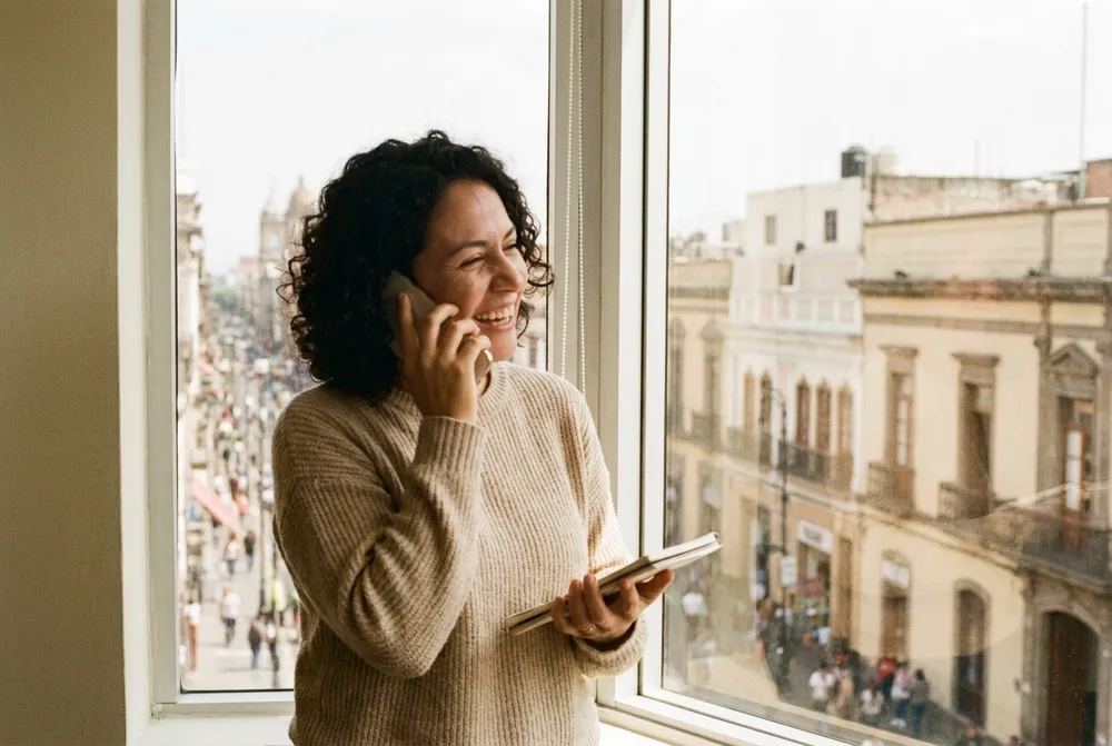 Especialista sonriendo en una llamada, con la calle de la ciudad abajo